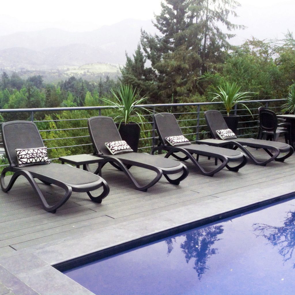 tres Reposeras Omega grafito NARDI frente a una piscina con Santiago de Chile de fondo