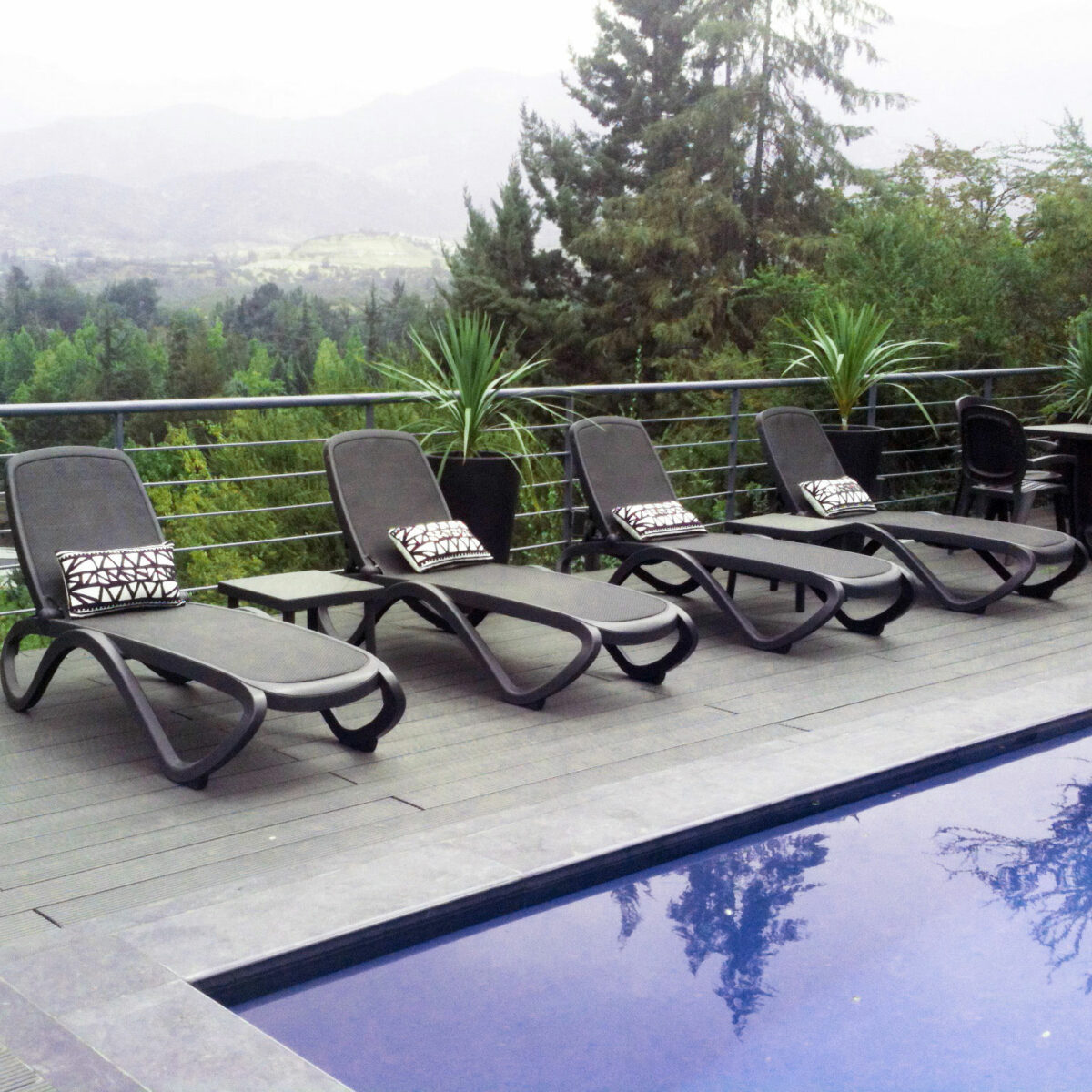 tres Reposeras Omega grafito NARDI frente a una piscina con Santiago de Chile de fondo