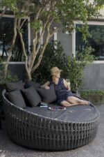 tumbonas para piscina ESTOCOLMO sobre UN Piso de piedras con UN arbol en El Fondo y unba persona sentada sobre El camastro